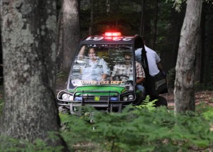 Emergency responders transport the victim through the woods to the ambulance. 