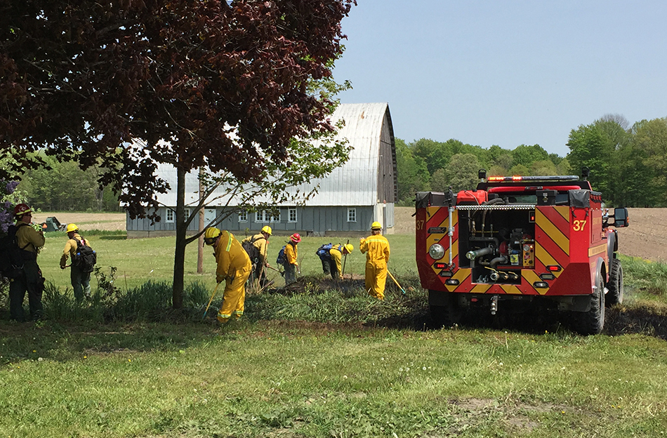 Firefighters extinguish Meade grass fire near buildings.